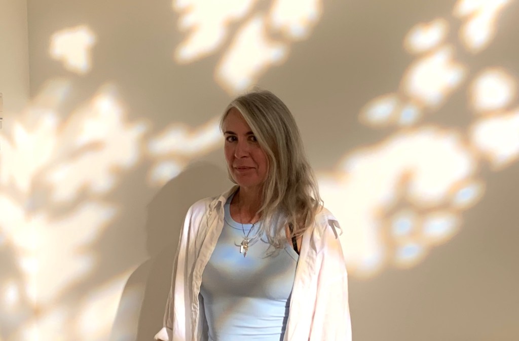 Image of Torch Hours against a cream wall with the light and shadow of a tree projected across Torch and the wall.